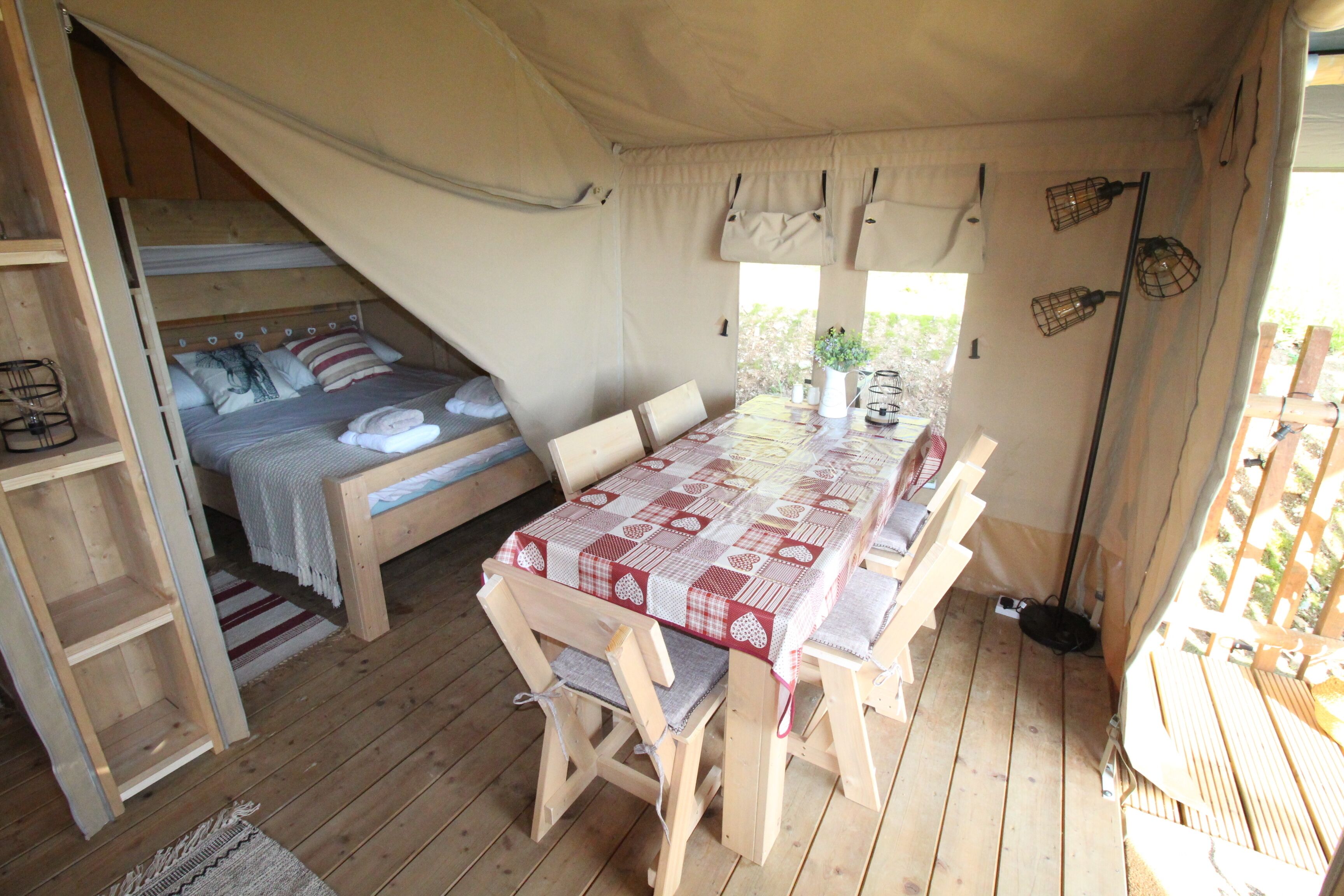 Alojamiento con carpa que incluye una cama individual, una mesa con sillas y un pequeño escritorio.