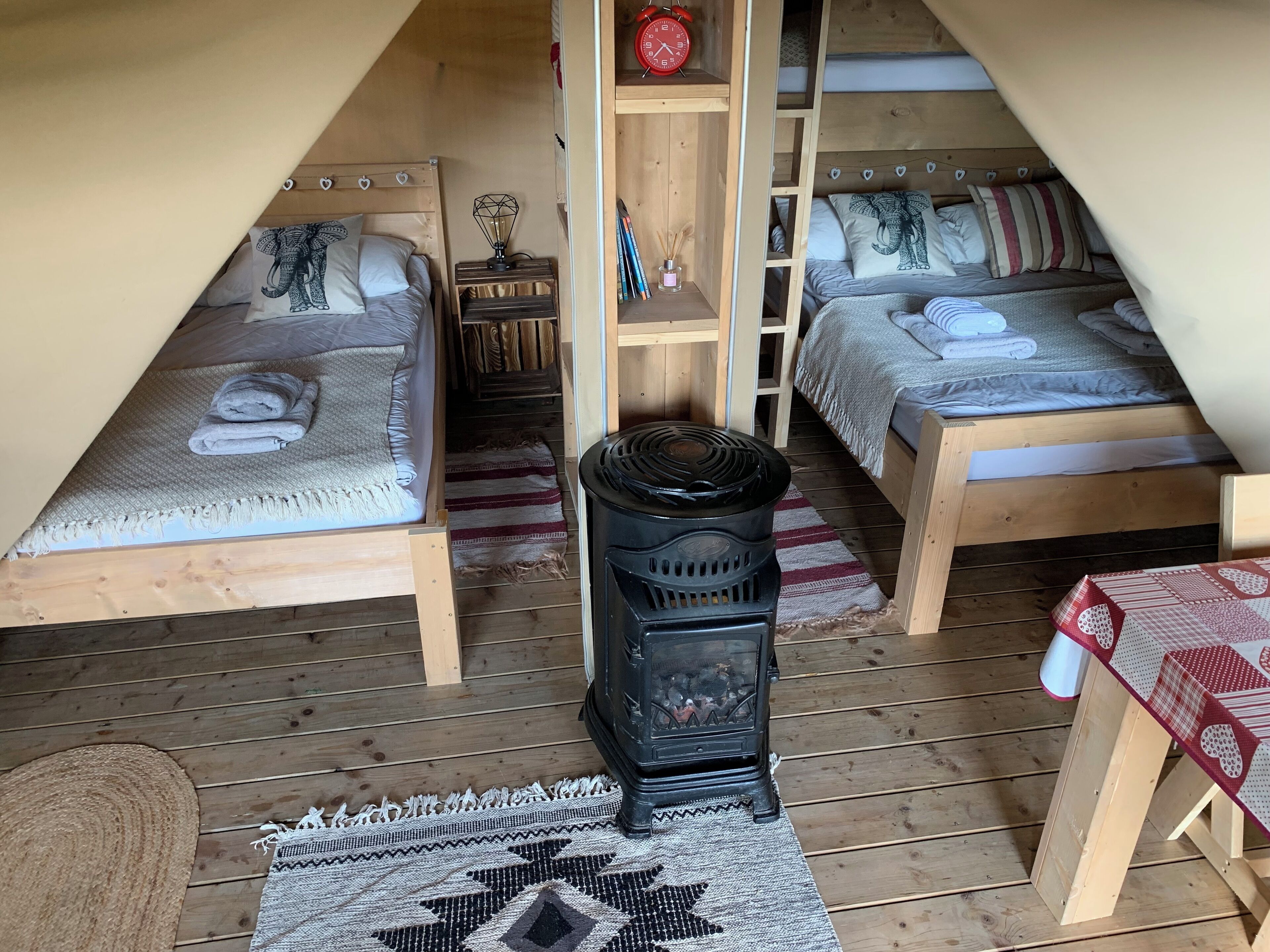 Um quarto de sótão aconchegante com duas camas, um fogão a lenha e uma pequena mesa.