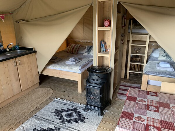 A cozy tented accommodation with a bed, a small kitchenette, and a wood-burning stove. - Torrent Walk Glamping (Dolgellau)