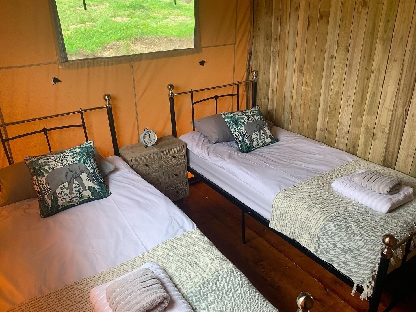 A room with two single beds, each with a pillow and a small bedside table.