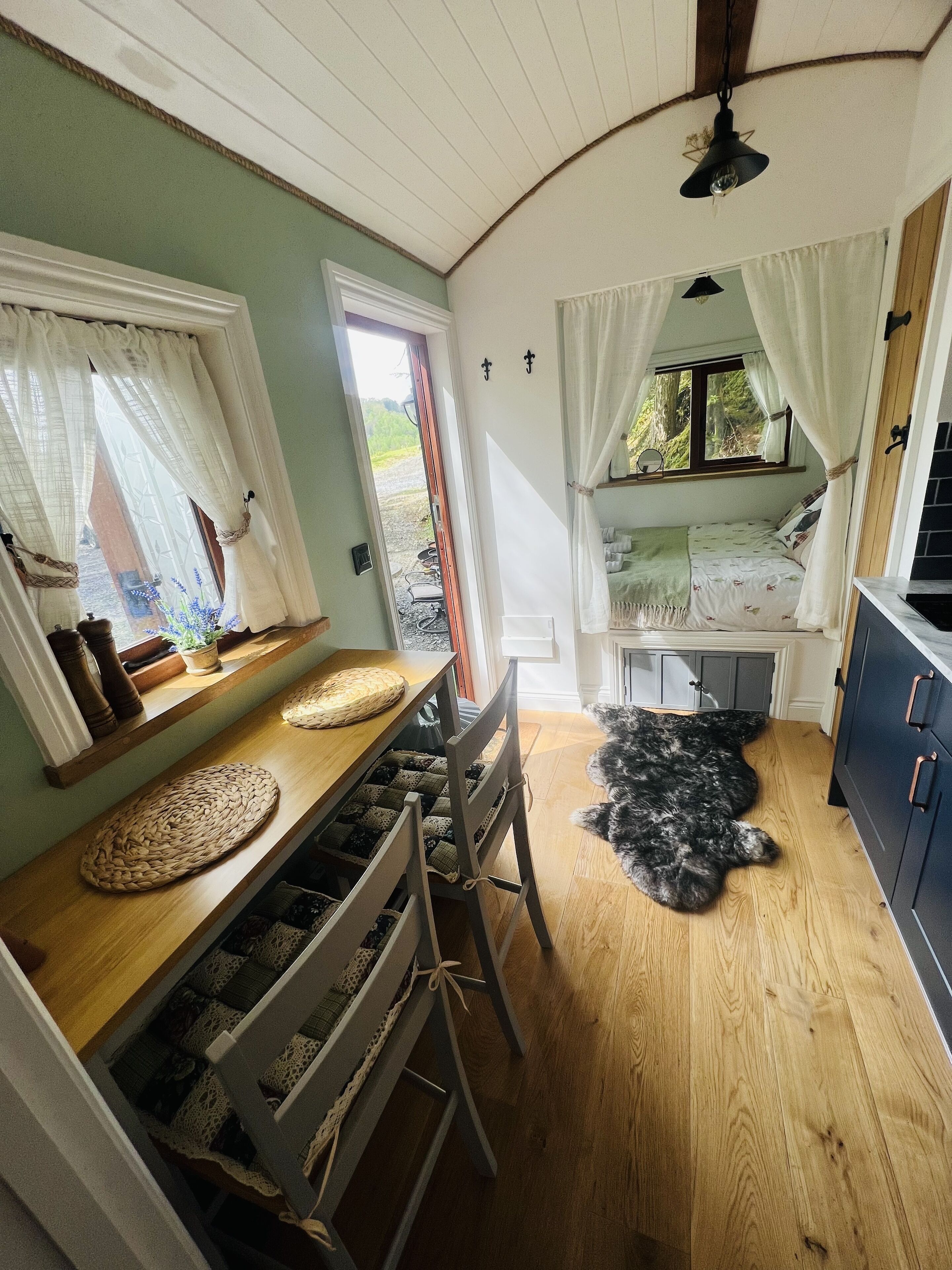 Una habitación acogedora con una mesa de comedor de madera, una cama con dosel y vistas al exterior a través de una ventana.