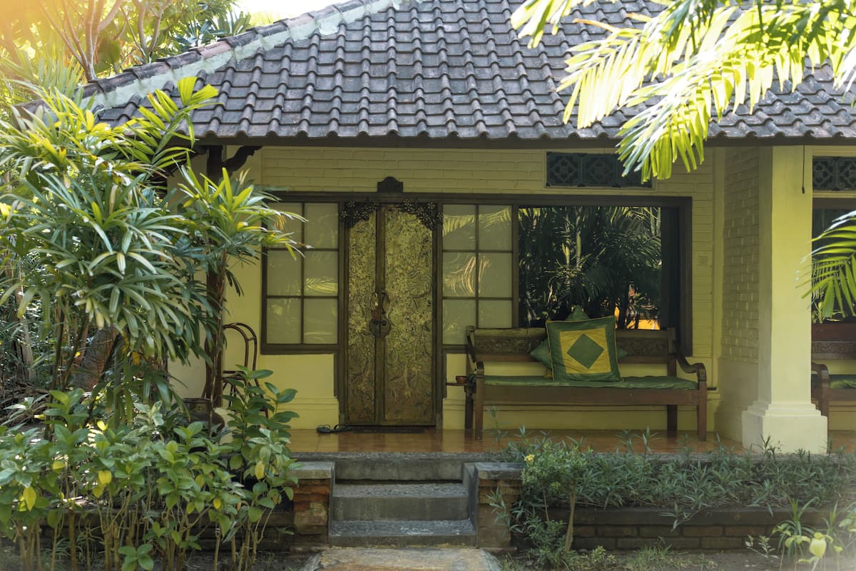 A traditional building with a tiled roof, a wooden bench, and a door with intricate designs.