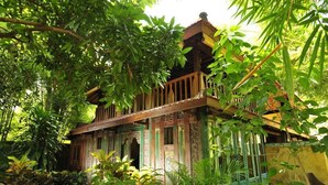 A traditional wooden house surrounded by lush greenery. - Pondok Sari Beach & Spa Resort (Pemuteran)