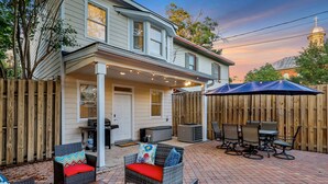 A covered patio area with wicker furniture and a barbecue grill.