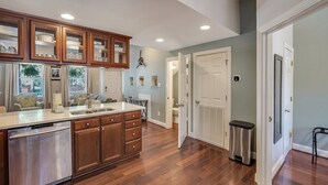 A modern kitchen with wooden cabinets, a stainless steel dishwasher, and a built-in oven.