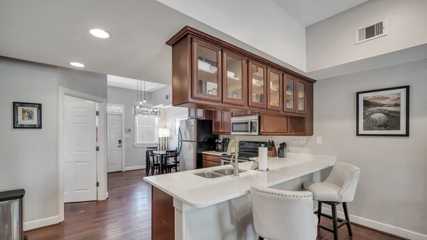 A modern kitchen with a central island, wooden cabinets, and a white countertop.