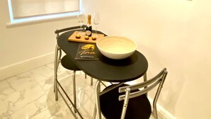 Un coin repas avec une table dressée pour deux personnes, comprenant un bol, un menu et deux verres de vin.