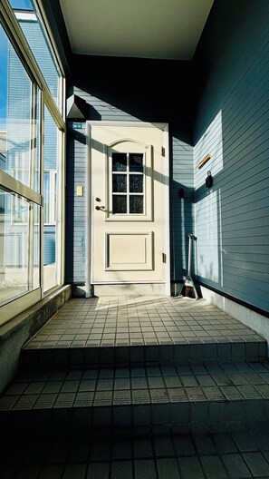 Un couloir avec une porte, une fenêtre et un sol carrelé.