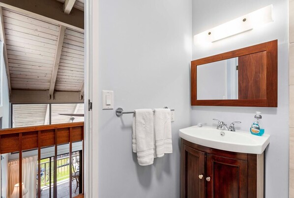 A bathroom with a wooden vanity, a white sink, a mirror, and a towel rack.