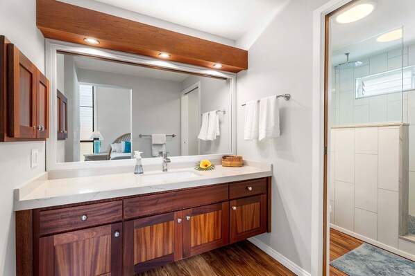 A modern bathroom with a wooden vanity, a large mirror, and a shower area.