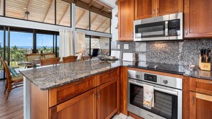 A modern kitchen with wooden cabinets, granite countertops, and stainless steel appliances including a Bosch oven and microwave.
