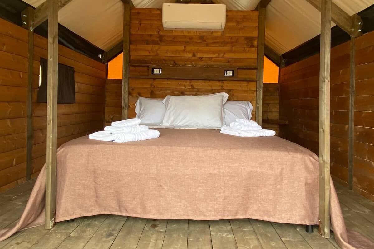 A wooden cabin bedroom with a bed, pillows, and a ceiling light fixture.