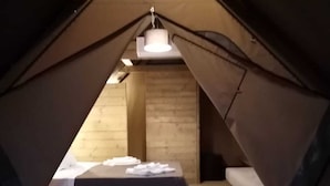 Pequeña habitación en ático, de forma triangular, con cama, banca y mesa.