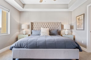 A bedroom with a large bed, two bedside tables with lamps, a tufted headboard, and a framed map on the wall. - Cottage Point 5 Bedroom Home (St. George)