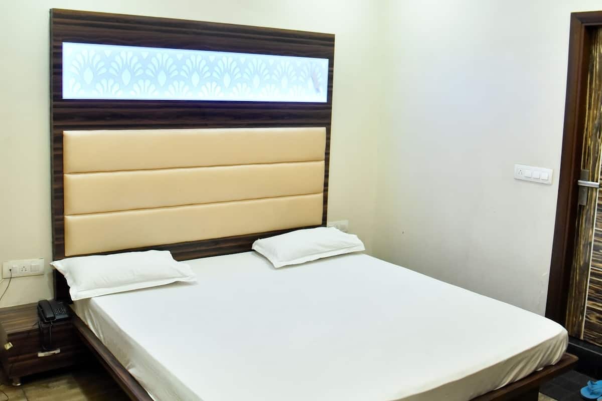 Un dormitorio pequeño y ordenado con cama, ventana con persianas, ventilador de techo y toma de corriente en la pared.