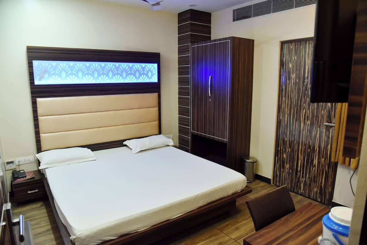 Habitación de hotel con una cama grande, un armario, un escritorio con silla y un televisor montado en la pared.