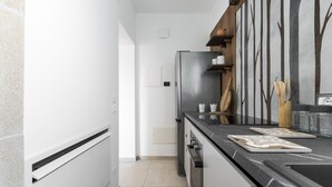 A modern kitchen with a stainless steel refrigerator, black countertops, and a minimalist design. - 3843 Petricore - Trilocale by Barbarhouse (Nardò)