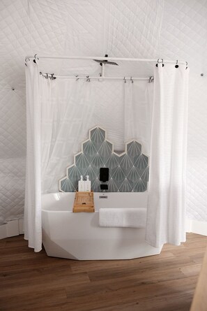 A bathroom with a white bathtub, a wooden tray, and a towel.