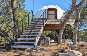 Une cabane dans les arbres avec un escalier en bois menant à une zone abritée.