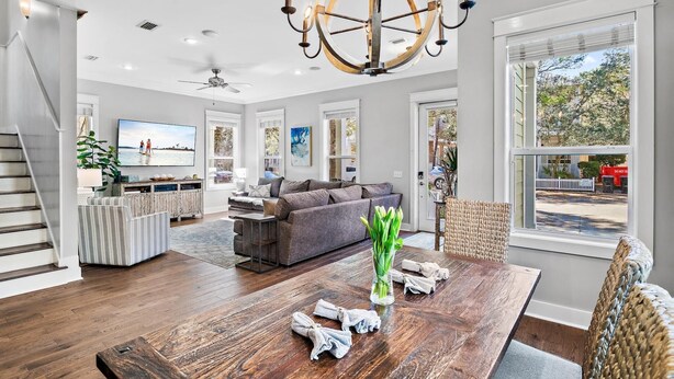 A spacious living room with a large wooden dining table, a grey sofa, and a chandelier. - Dog-Friendly Home with Community Pools (Santa Rosa Beach)