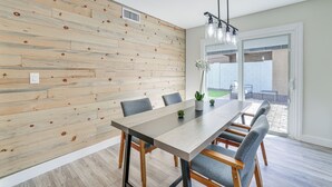 A modern dining area with a wooden wall, a long table, and grey chairs. - Furnished Patio! Family-friendly Retreat in Tempe (Tempe)