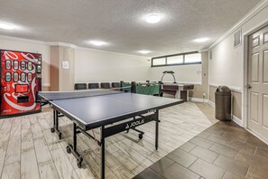 Ein Tischtennistisch in einem Raum mit Fliesenboden, einem Mülleimer und einer Tür.