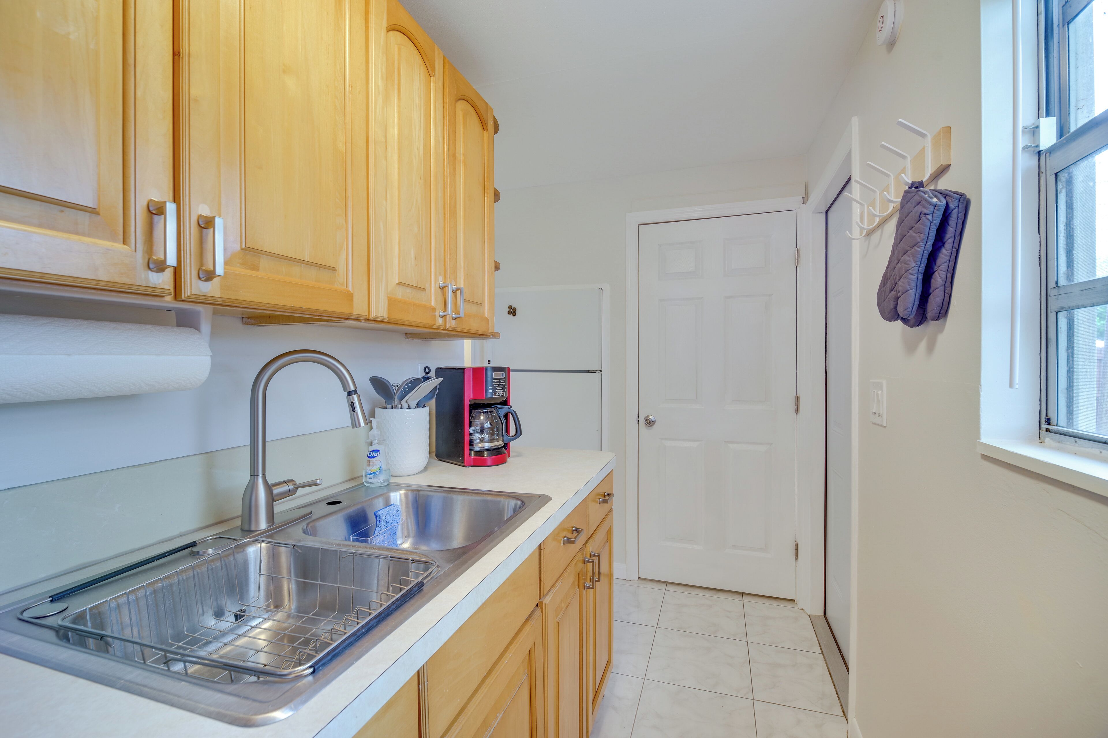 A kitchen with wooden cabinets, a stainless steel sink, and a coffee maker.