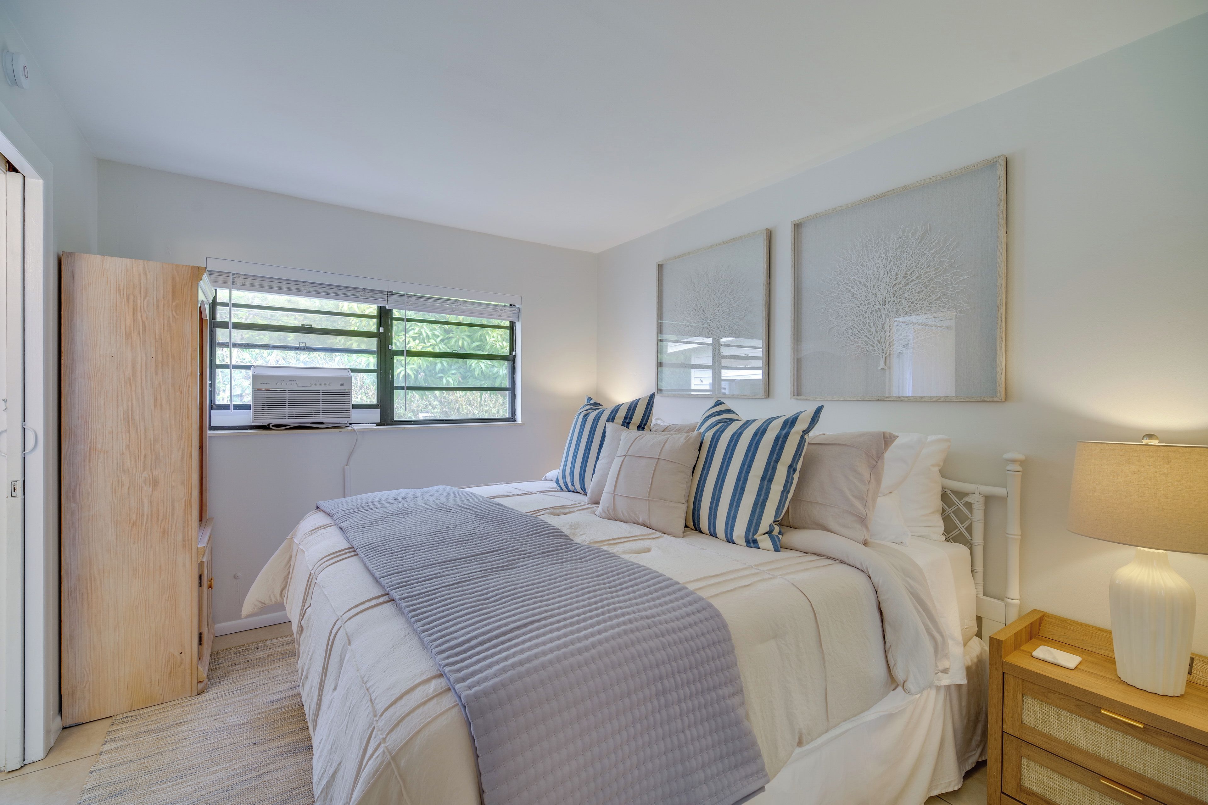 Un dormitorio con cama, mesita de noche y ventana con persianas.