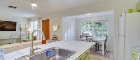 A modern kitchen with a double sink, green cabinets, and a dining area with a table and chairs.