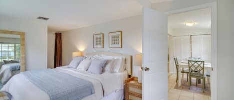 Een slaapkamer met een bed, nachtkastje en uitzicht op de eetruimte.