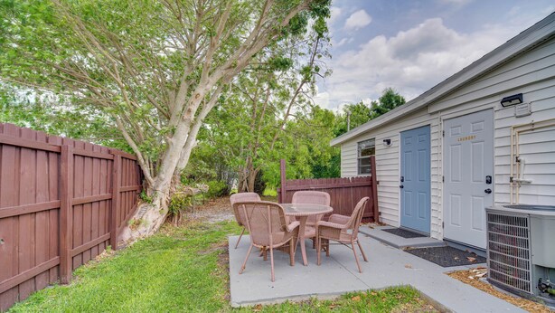 A patio with wicker furniture, a wooden fence, and a house with a laundry room. - Vero Beach Studio w/ Shared Patio ~ 3 Mi to Beach! (Vero Beach)