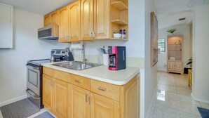 A kitchen with wooden cabinets, a stainless steel sink, and a built-in oven. - Vero Beach Studio w/ Shared Patio ~ 3 Mi to Beach! (Vero Beach)
