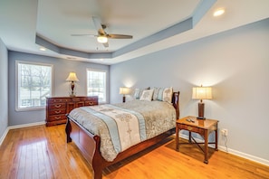A bedroom with a wooden bed, two bedside tables with lamps, a dresser, and a ceiling fan. - Louisville Retreat w/ Deck ~ 11 Mi to Downtown! (Louisville)