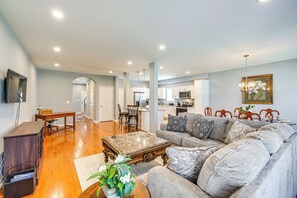 A spacious living room with a large grey sofa, a wooden coffee table, and a dining area with a wooden table and chairs. - Louisville Retreat w/ Deck ~ 11 Mi to Downtown! (Louisville)