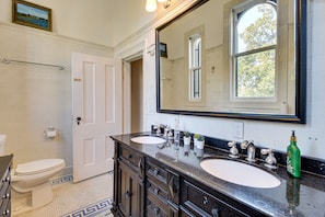 A bathroom with two sinks, a large mirror, and a toilet.