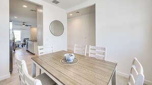 A dining area with a wooden table, white chairs, and a round mirror on the wall. - Maricopa Home w/ Putting Green & Covered Patio! (Maricopa)