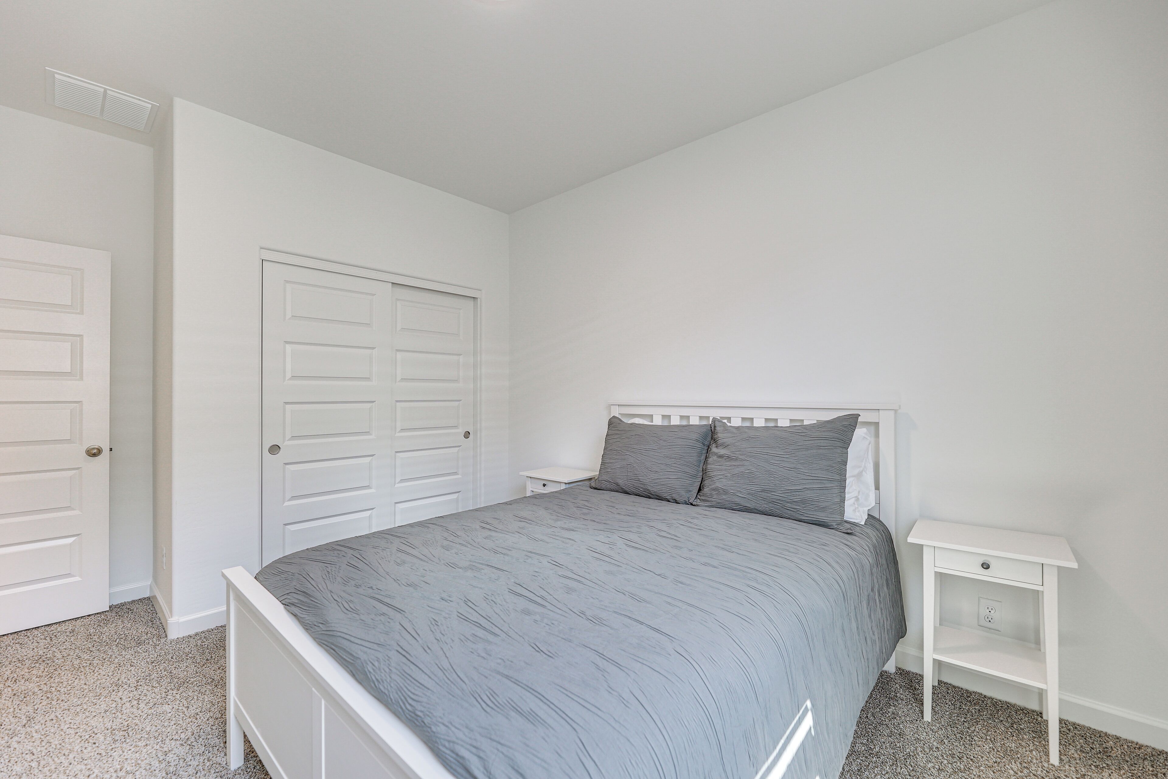 Une chambre à coucher avec un lit, une table de chevet et une porte.