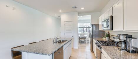 A modern kitchen with granite countertops, stainless steel appliances, and white cabinetry.