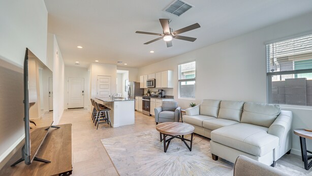 A modern living room with a sofa, coffee table, and TV stand. - Maricopa Home w/ Putting Green & Covered Patio! (Maricopa)