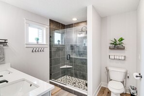 Enjoy a refreshing shower in the bathroom, featuring a glass-enclosed shower, pebble-patterned floor, and a large window.
