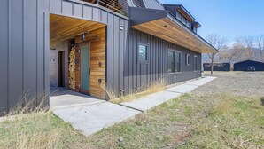 Een modern gebouw met een houten voordeur, grote ramen en een overdekte veranda.