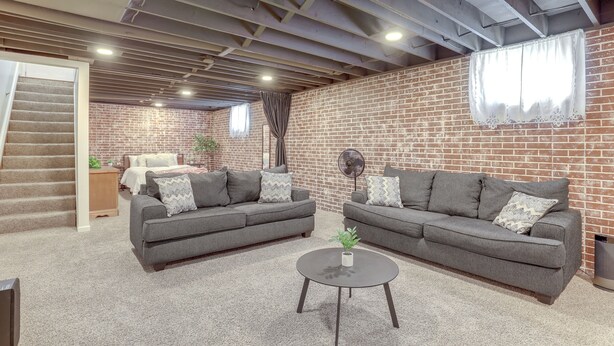 A spacious living room with two grey sofas, a small coffee table, and a brick wall. - Family-friendly Lincoln Home w/ Sandbox & Grill! (Lincoln)