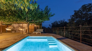 A swimming pool with steps leading into it, surrounded by a wooden deck and a metal railing.