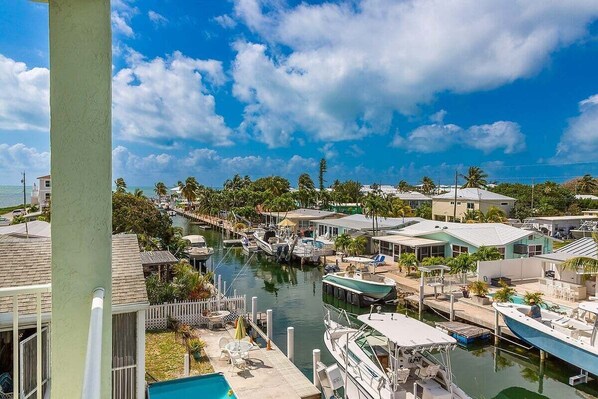 A marina with boats docked, a swimming pool, and houses with a view of the water.