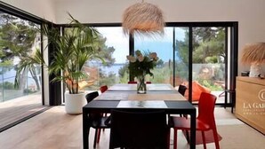 Uma área de jantar moderna com uma mesa grande, cadeiras e um lustre.