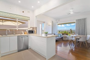 A modern kitchen with a dishwasher, a microwave, and a large window overlooking a scenic view.