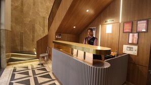 Un comptoir d’accueil au design moderne, un comptoir d’accueil en bois, une horloge et une enseigne indiquant « accueil ».