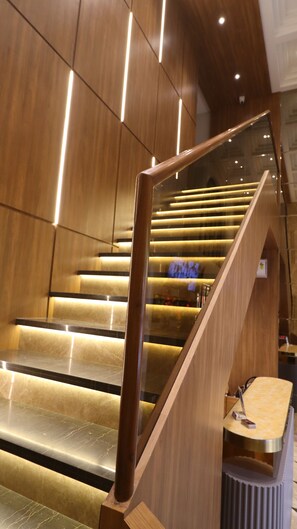 A modern staircase with wooden railings and illuminated steps. - The UBE Residency (Mumbai)
