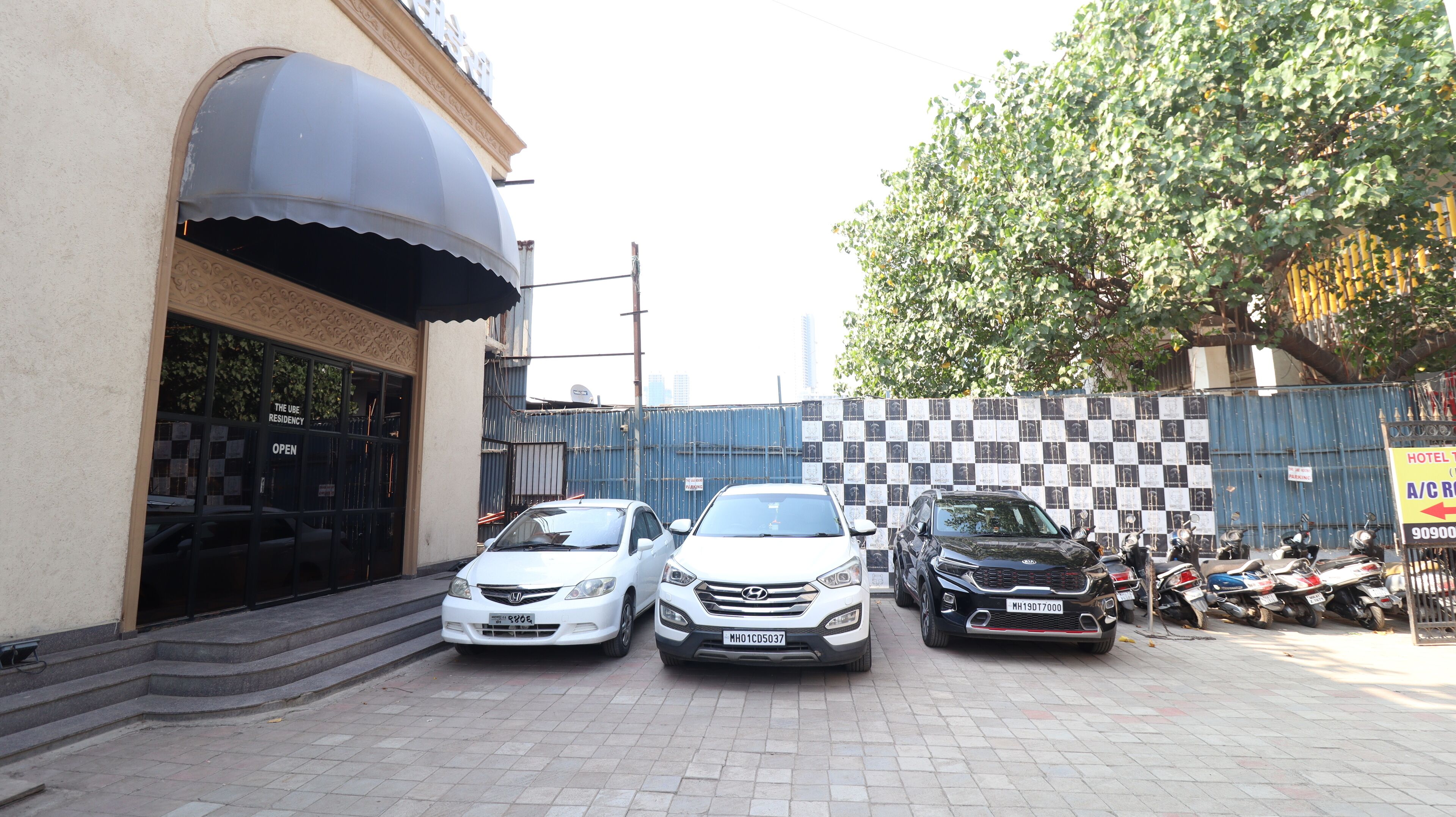 A parking area with three cars and a row of parked motorcycles.