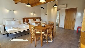 A bedroom with a bed, bedside tables, and a wooden dining table with chairs. - Quinta da Bornacha (Vila Real Santo Antonio)